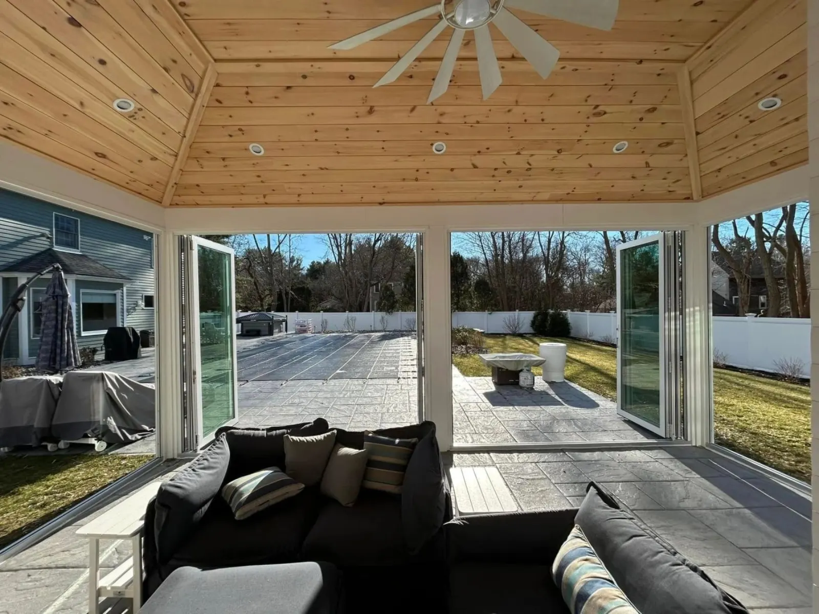 Finished pool house interior with pine ceiling and folding glass doors opening to the patio